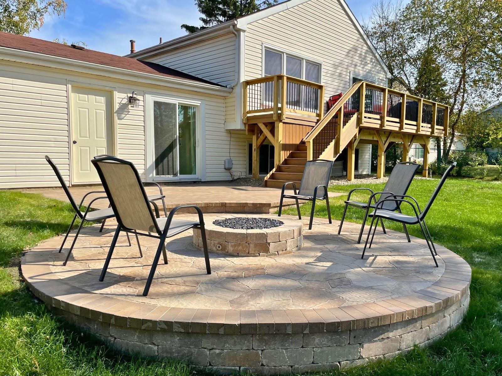Lake Zurich backyard with a wood deck and paver patio with a firepit. 